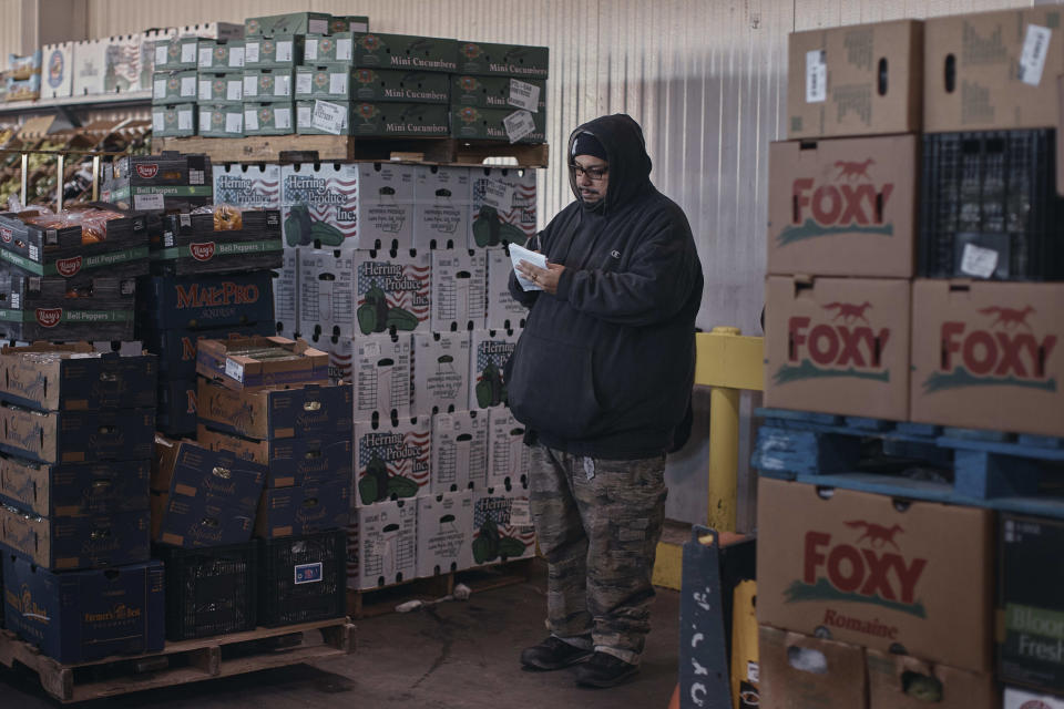 A man take notes in between boxes of fresh fruits and vegetables at S. Katzman Produce inside the Hunts Point Produce Market on Tuesday, Nov. 22, 2022, in the Bronx borough of New York. Hunts Point's wholesalers distribute 2.5 billion pounds of produce a year, with about 30 million pounds having moved on Tuesday alone. The produce ends up at places like Whole Foods, high-end grocers and specialty markets, as well smaller mom-and-pop outlets. Thanksgiving is especially busy time of year because the quintessentially American feast is universally celebrated across the United States. (AP Photo/Andres Kudacki)