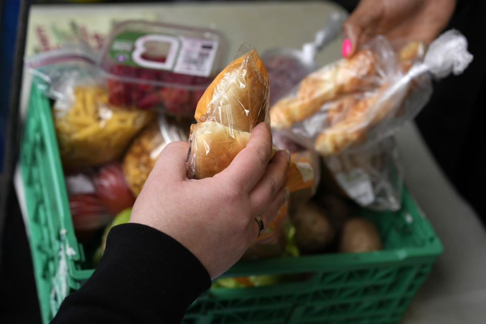 A woman, left, collects food at the Community Food Hub in Hackney, London, Thursday, June 13, 2024. Since calling a general election, British Prime Minister Rishi Sunak has been at pains to repeat a key message on the campaign trail: The economy is turning a corner, inflation is down, and things are looking up. That’s not the reality for millions across the U.K. still feeling the squeeze from high food, energy and housing prices. (AP Photo/Kin Cheung)