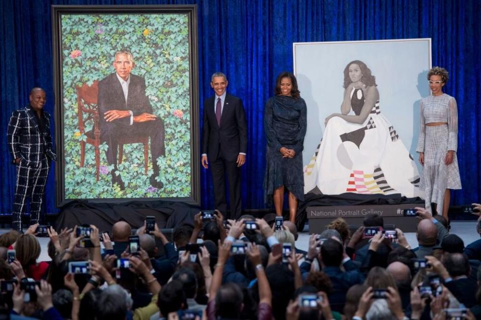 Barack and Michelle Obama (center) standing in front of their portraits in Washington, D.C., along with artists Kehinde Wiley (left) and Amy Sherald (right).