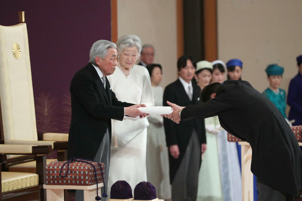 Japan's Emperor Akihito hands over his statement to the grand chamberlain after speaking to other members of the royal families and top government officials during the ceremony of his abdication at the Imperial Palace in Tokyo, Tuesday, April 30, 2019. The 85-year-old Akihito ends his three-decade reign on Tuesday as his son Crown Prince Naruhito will ascend the Chrysanthemum throne on Wednesday. (Japan Pool via AP)