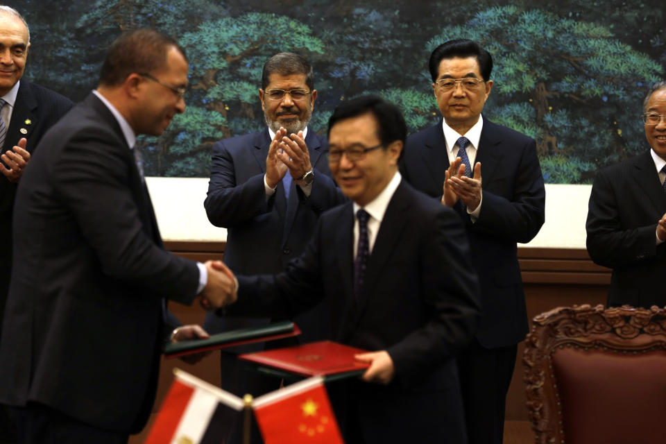 Egyptian President Mohammed Morsi, center left, and Chinese President Hu Jintao, center right, applaud as officials from both countries exchange documents during a signing ceremony at the Great Hall of the People in Beijing, China, Tuesday, Aug. 28, 2012. China is hosting Egypt's newly elected president despite its uneasiness with the Arab Spring revolution that helped bring him to power, while the new leader seeks to shore up his country's flagging economy. (AP Photo/Ng Han Guan)