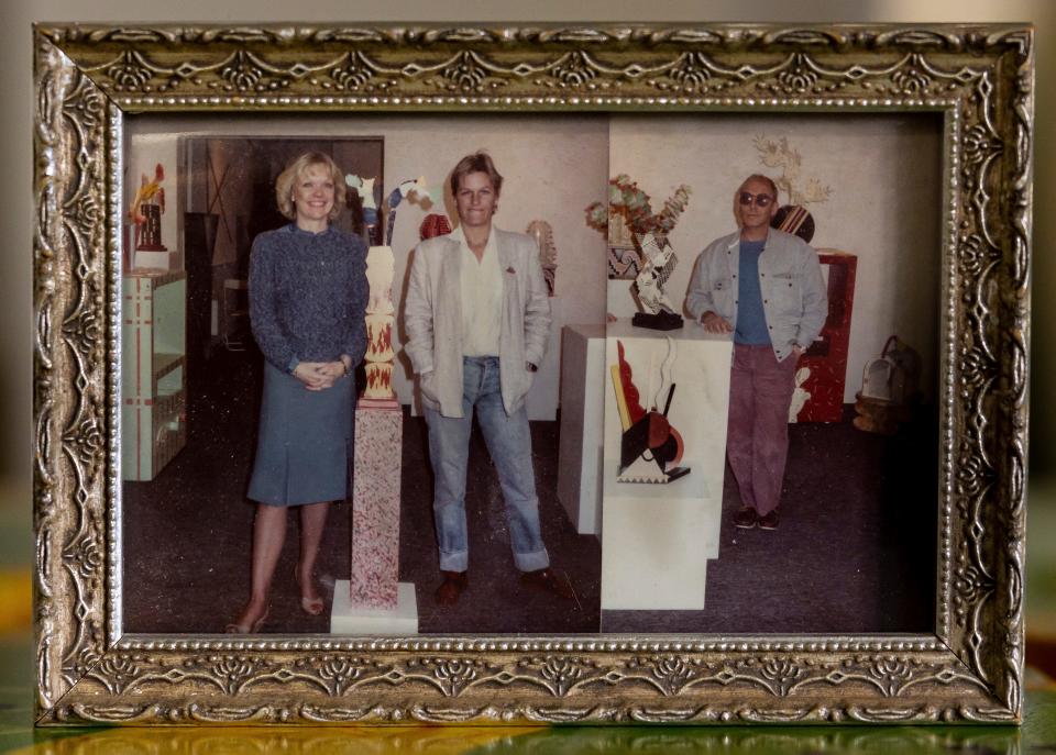 A picture of a framed photo that shows three people standing in an art gallery,