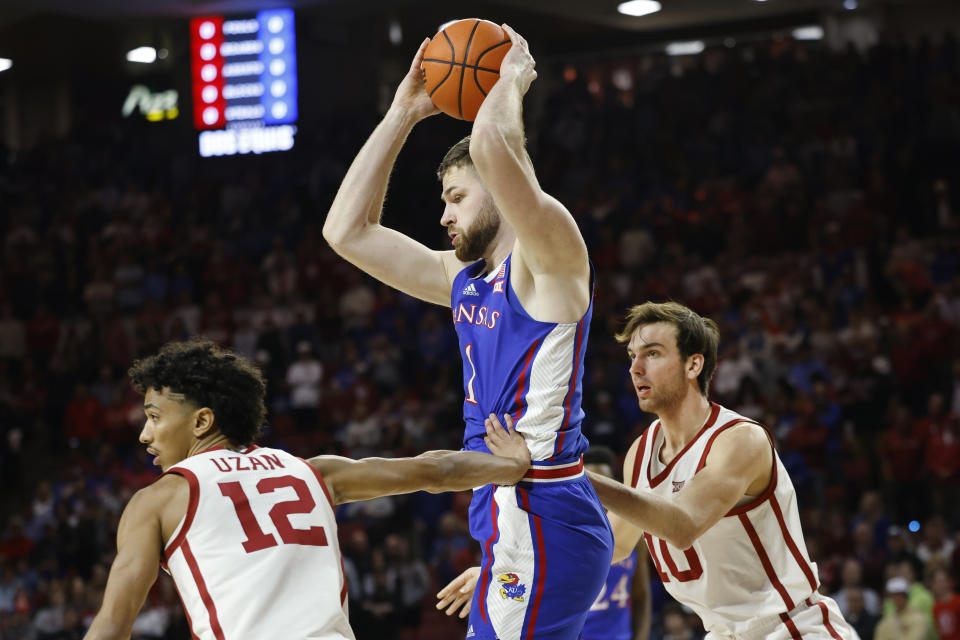 Kansas center Hunter Dickinson (1) goes against Oklahoma guard Milos Uzan (12) and forward Sam Godwin (10) during the first half of an NCAA college basketball game Saturday, Feb. 17, 2024, in Norman, Okla. (AP Photo/Garett Fisbeck)