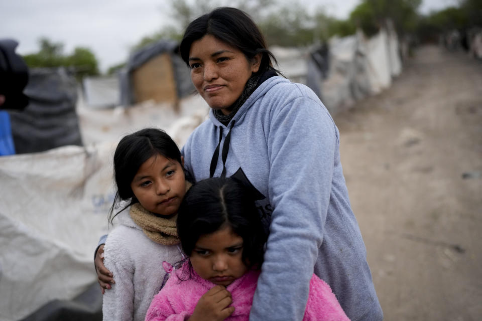 Paola Aguirre abraza a sus hijas Keila, a la derecha, y Loana fuera de su casa en Salta, Argentina, el miércoles 4 de octubre de 2023. Aguirre, que vive en una casita levantada con maderas cerca de un vertedero, tiene puesta su esperanza en el candidato presidencial Javier Milei, un economista y legislador instigador que se describe a sí mismo como un anarco-capitalista y que dice que la respuesta a la creciente inflación anual que ahora ronda el 140% pasa por eliminar el Banco Central y dolarizar la economía. (AP Foto/Natacha Pisarenko)