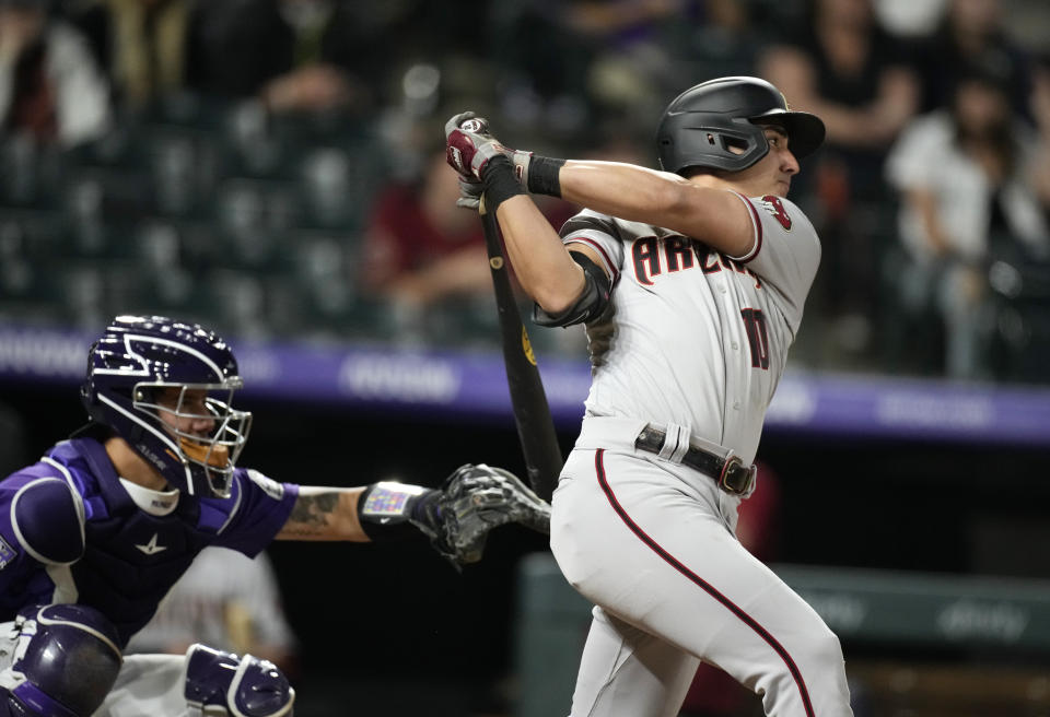 Arizona Diamondbacks' Josh Rojas, right, connects for a sacrifice fly to bring in a run off Colorado Rockies relief pitcher Jordan Sheffield in the eighth inning of a baseball game Friday, May 21, 2021, in Denver. (AP Photo/David Zalubowski)