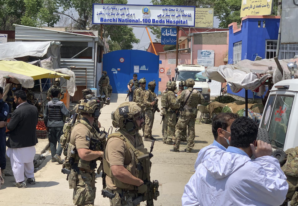 Afghan and foreign security personnel stand guard in front of a hospital after gunmen attacked, in Kabul, Afghanistan, Tuesday, May 12, 2020. Gunmen stormed a maternity hospital in the western part of the Afghan capital, setting off a gun battle with the police and several people were reported wounded. (AP Photo/Rahmat Gul)