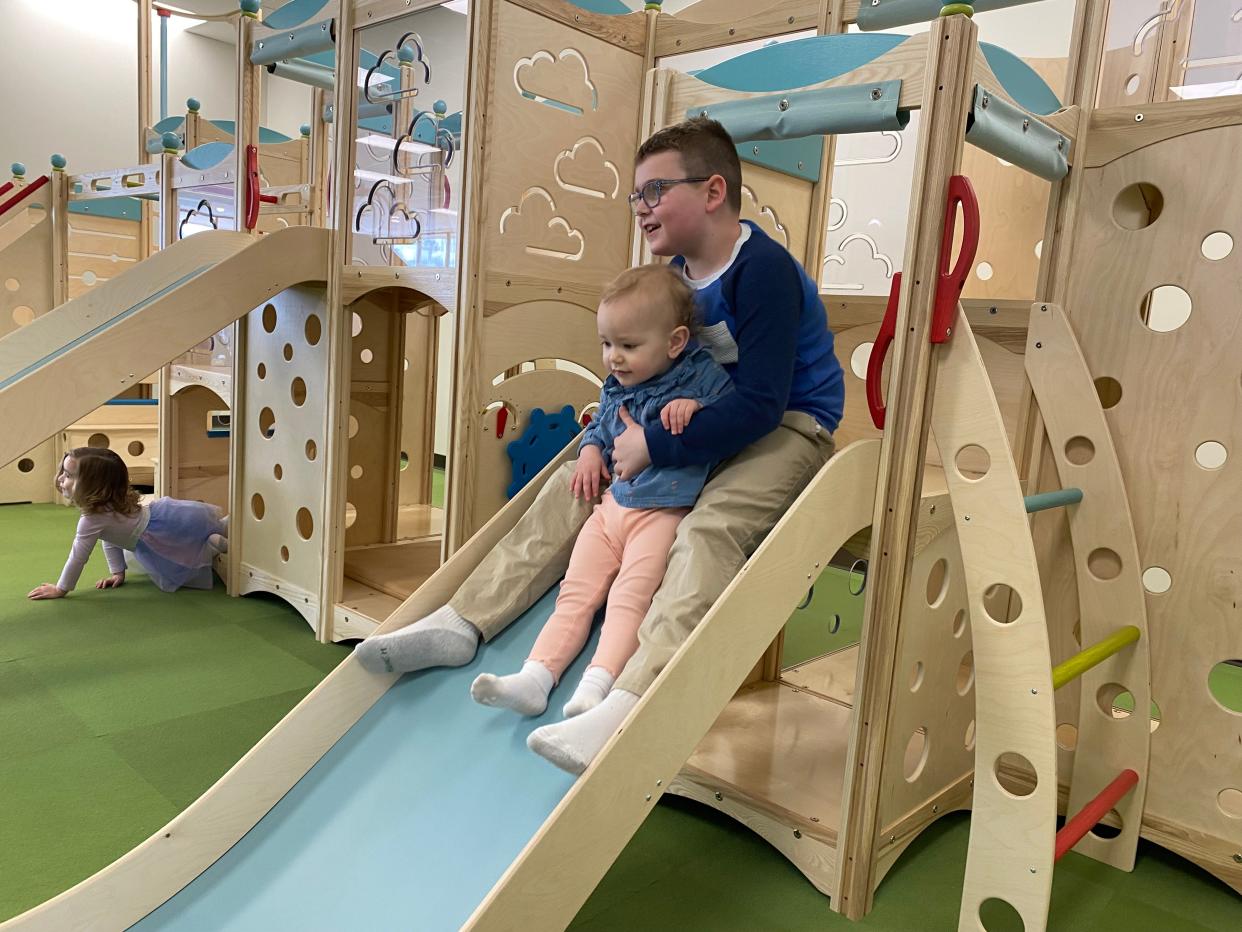 Daniel Kelley holds Maeve Pittsley as they go down a slide at My Village Playhouse on Monday, March 25, 2024.