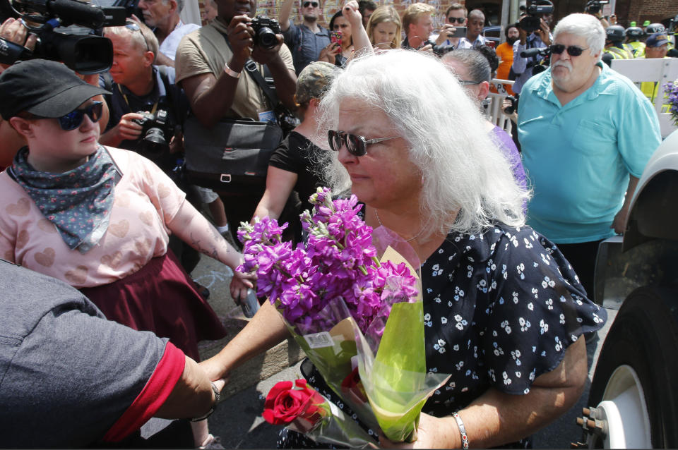 Susan Bro, center, mother of Heather Heyer who was killed during last year's Unite the Right rally, and her husband, Kim, right, speak to supporters after laying flowers at the spot her daughter was killed in Charlottesville, Va., Sunday, Aug. 12, 2018. Bro said there's still "so much healing to do." She said the city and the country have a "huge racial problem" and that if it's not fixed, "we'll be right back here in no time." (AP Photo/Steve Helber)