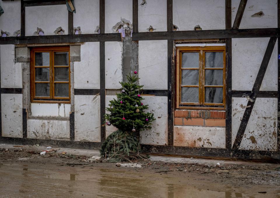 A Christmas tree leans against a damaged house in the village of Schuld in the Ahrtal valley, southern Germany, Tuesday, Dec.14, 2021. Amid the mud and debris still clogging the streets from last summer's devastating floods, residents of the Ahr Valley in western Germany are trying to spark some festive cheer with Christmas trees. (Photo/Michael Probst)