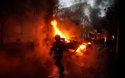 Firemen are at work to extinguish a burning car on the sideline of a demonstration by Yellow vests (Gilets jaunes) protesters against rising oil prices and living costs, on December 1, 2018 in Paris - Credit: ABDULMONAM EASSA/AFP