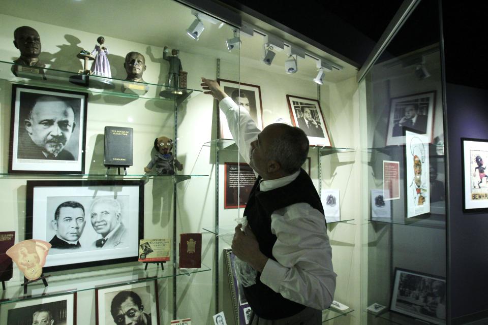 In a March 14, 2012 photo, David Pilgrim, the founder and curator who started building the Jim Crow Museum of Racist Memorabilia, adjusts a display at the museum in Big Rapids, Mich. The museum says it has amassed the nation’s largest public collection of artifacts spanning the segregation era, from Reconstruction until the civil rights movement, and beyond. (AP Photo/Carlos Osorio)