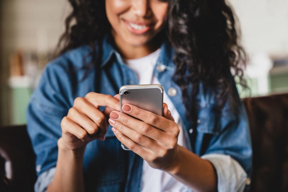 cropped shot of a woman in denim jacket scrolling on phone