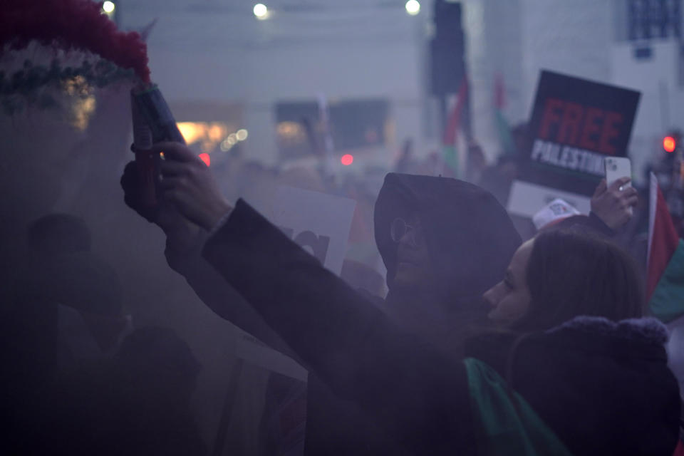 Flares are let off by protesters as others hold flags and placards during a pro-Palestinian demonstration in Trafalgar Square in London, Saturday, Nov. 25, 2023. (AP Photo/Alberto Pezzali)