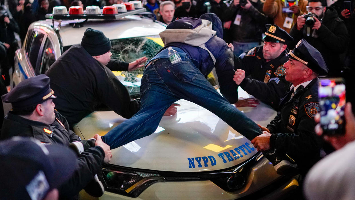 Police officers try to remove a protester sprawled on to of a police vehicle.
