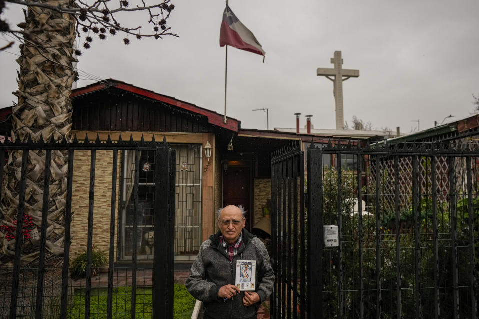 Sergio Gómez Martínez poses for portrait holding a portrait of the late Gen. Augusto Pinochet outside his home in Santiago, Chile, Tuesday, Aug. 22, 2023. The retired accountant said that “fortunately, Augusto Pinochet led the coup” against Allende’s socialist government, arguing that his economic wellbeing improved under the right-wing military government “because there was order, employment, and the countryside and industries began to produce.” (AP Photo/Esteban Felix)