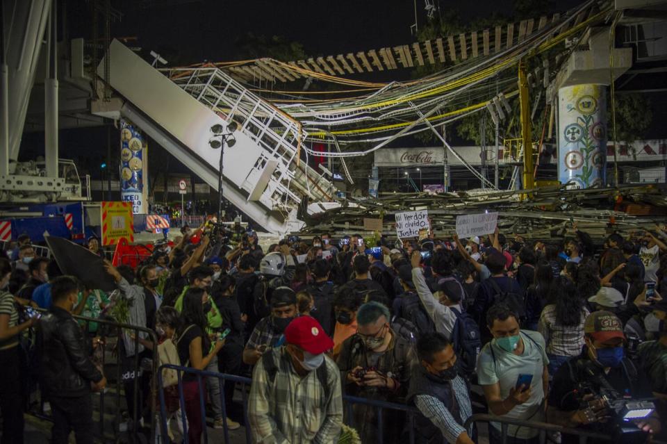 People stand near debris and under hanging wires.