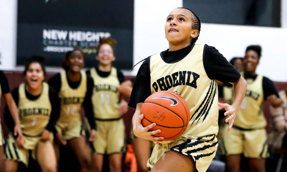 Siyhann Sharp of New Heights Charter takes a layup, as teammates are seen cheering in the background, during a game against Codman Academy on Monday, Jan. 9, 2023.