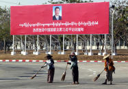 Municipal workers sweep on a road near a welcoming billboard to Chinese President Xi Jinping Friday, Jan. 17, 2020, in Naypyitaw, Myanmar. China's President Xi Jinping was heading to Myanmar on Friday for a state visit likely to deepen the countries' already close bilateral relations at a critical time. (AP Photo/Aung Shine Oo)