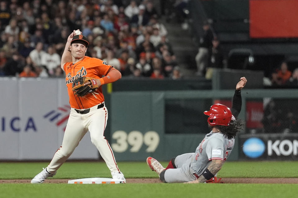 San Francisco Giants shortstop Casey Schmitt, left, throws to first base after forcing out Cincinnati Reds' Jonathan India at second base on a double play hit into by Elly De La Cruz during the seventh inning of a baseball game in San Francisco, Friday, May 10, 2024. (AP Photo/Jeff Chiu)