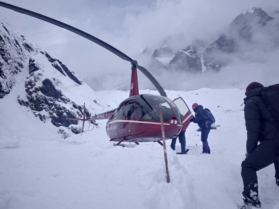 In this Saturday, Jan. 18, 2020 photo, trekkers are being rescued in a helicopter a day after an avalanche hit Mount Annapurna trail in Nepal. Special army and government rescue personnel were searching again on Monday for four South Korean trekkers and their three Nepali guides lost since an avalanche swept a popular trekking route in Nepal's mountains. (AP Photo/Phurba Ongel Sherpa)