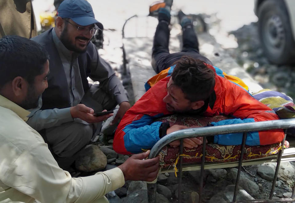 In this photo provided by Gilgit Baltistan regional police department, a mountaineer receives initial treatment following his rescue, at a helipad in the town of Imit, Ghizer district of Gilgit Balistan region, Pakistan, Tuesday, Jun 18, 2019. A Pakistani army helicopter rescued on Tuesday four Italian and two Pakistani climbers stranded at an altitude of around 5,300 meters (17,390 feet) in the country's north, after an avalanche struck the team the previous day, a mountaineering worker said. A Pakistani member of the team was killed. (Gilgit Baltistan regional police department via AP)