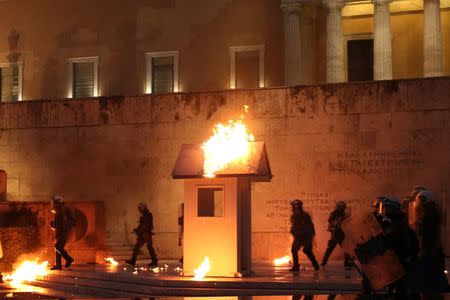 Riot police walk among flames by petrol bombs as a guard post of the Tomb of the Unknown Soldier burns during clashes outside the parliament building as Greek lawmakers vote on the latest round of austerity Greece has agreed with its lenders, in Athens, Greece, May 18, 2017. REUTERS/Costas Baltas