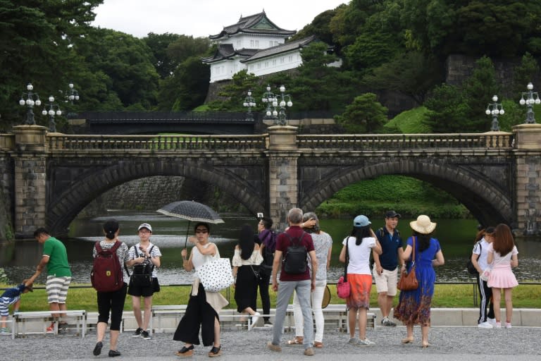 Tourists are seen in front of the Imperial Palace in Tokyo on August 8, 2016