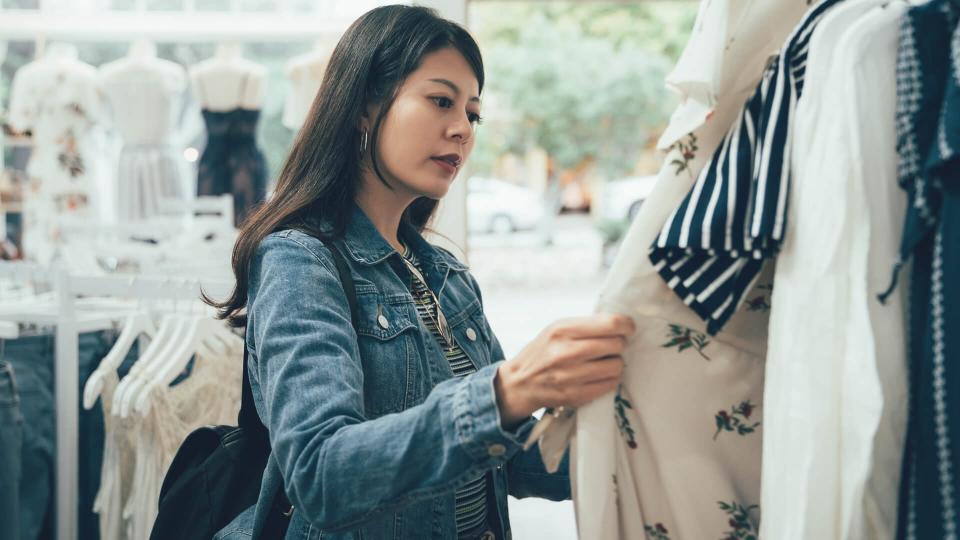 Young korean woman looking through new clothes during shopping in dress store on christmas sale.