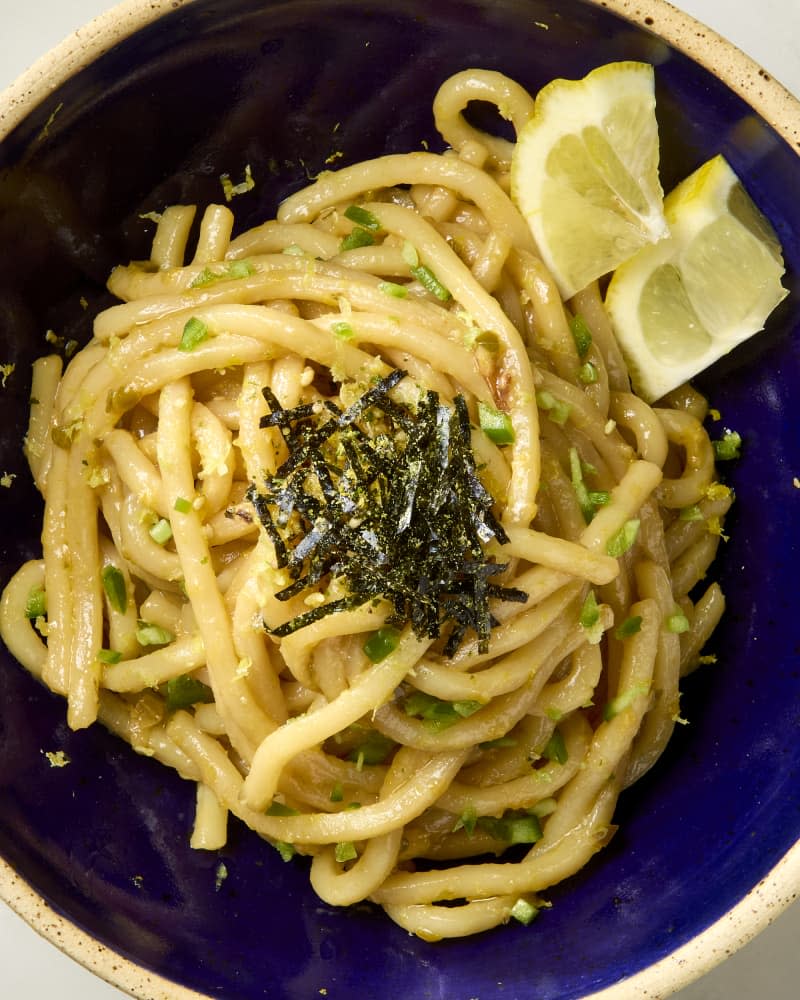 Lemon jalapeno udon noodles in a bowl topped with furikake and served with lemon.