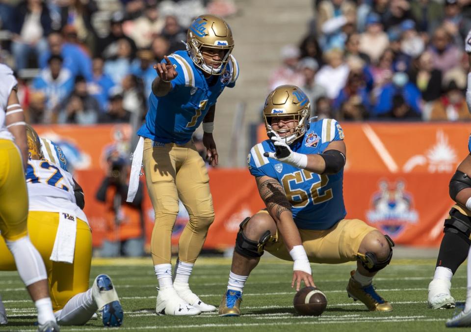 Center Duke Clemens squats and touches the football while talking with Dorian Thompson-Robinson during the Sun Bowl