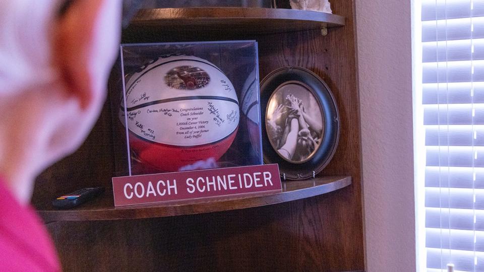 Bob Schneider points to a commemorative basketball presented to him following his 1,000 career victory in 2004.