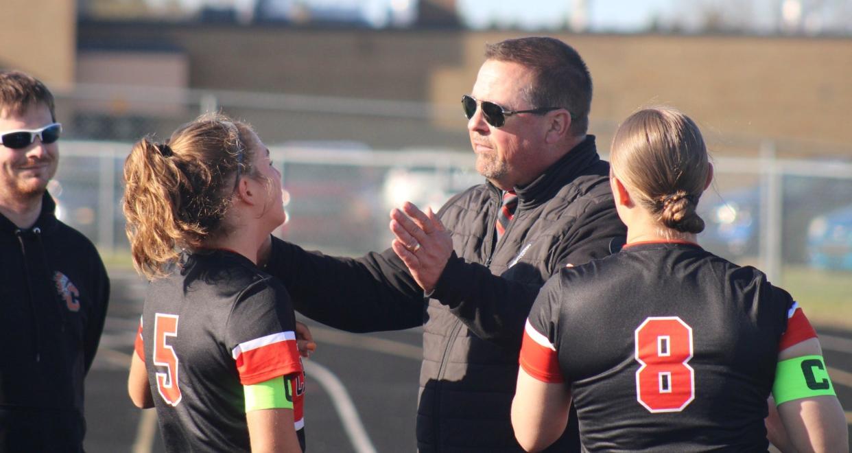 Cheboygan senior Autumn Gingrich (5), along with fellow senior defender and captain Bella Lail (8), listen to coach Tom Markham during halftime of a recent game in Cheboygan. Gingrich and Lail have formed a solid defensive partnership this season.