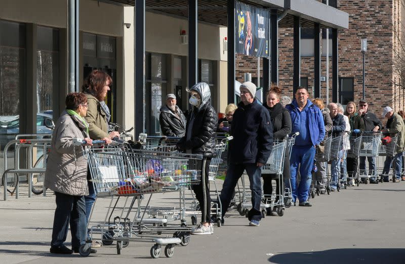 FILE PHOTO: Shoppers leave as others wait in a queue to enter a supermarket in Schulzendorf near Berlin, during the coronavirus disease (COVID-19) outbreak