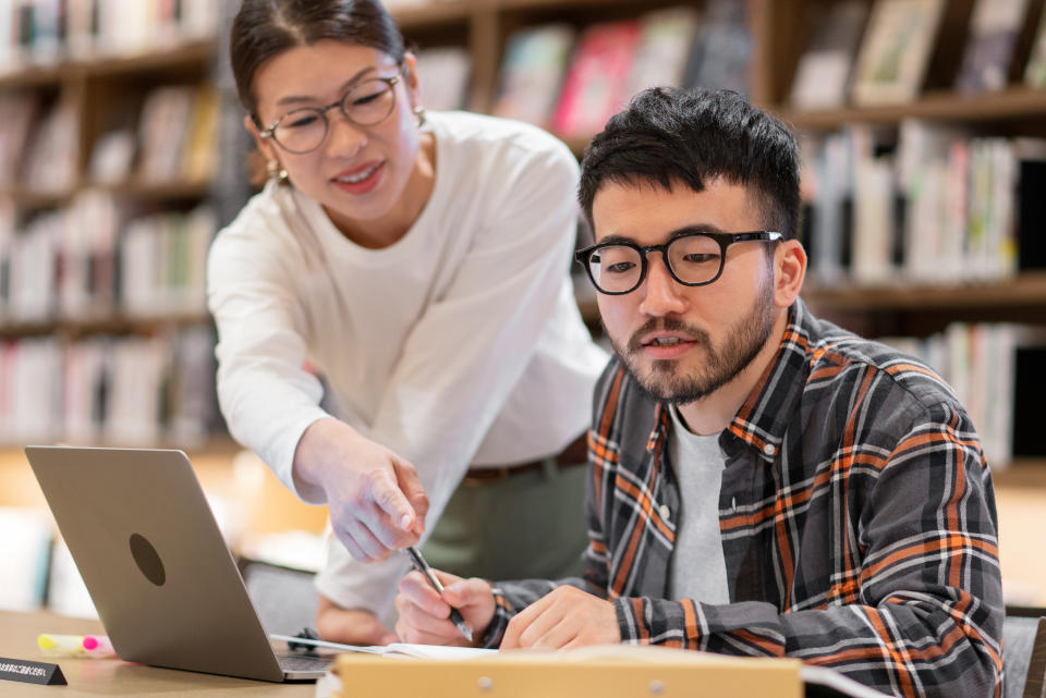 A professor advises a student during a visit to the library