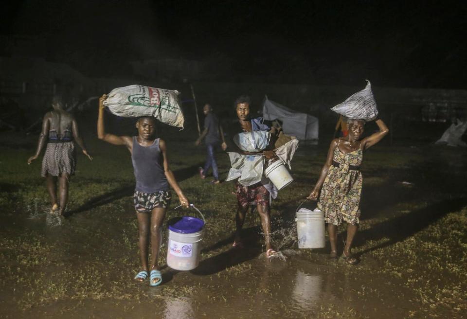 People affected by Saturday's earthquake walk under the rain of Tropical Depression Grace at a refugee camp in Les Cayes, Haiti, Monday, Aug. 16, 2021.