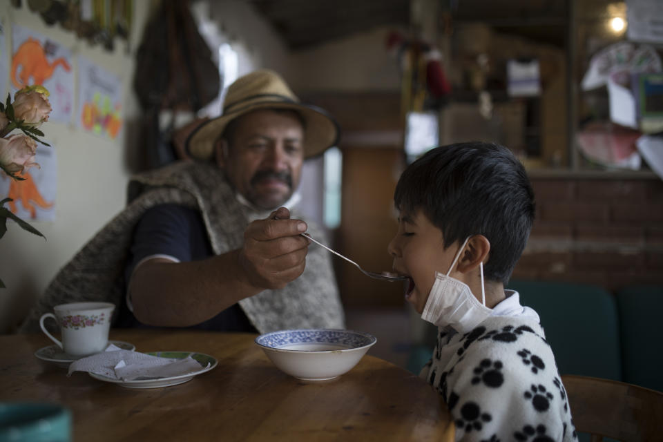 Jaime Ramirez feeds his son Gabriel in Chia, Colombia, March 23, 2020. (AP Photo/Ivan Valencia)