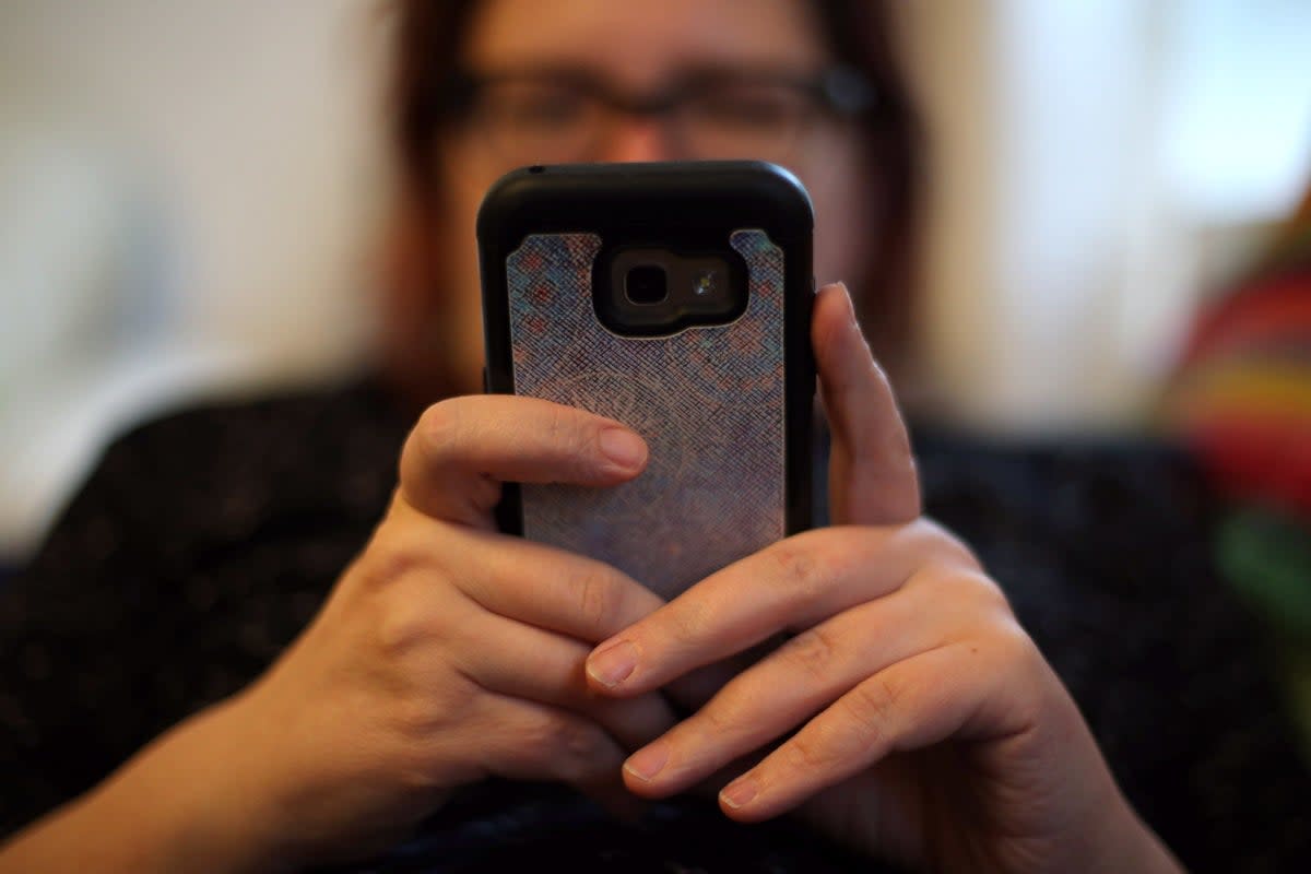 A woman using her mobile phone (Yui Mok / PA)