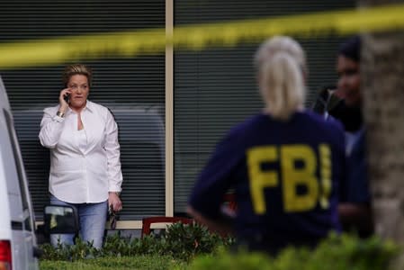 Victoria Nemerson, General Counsel for Alpha Medical Consulting, is seen on the phone as an FBI agent looks on outside Clio Laboratories in Lawrenceville