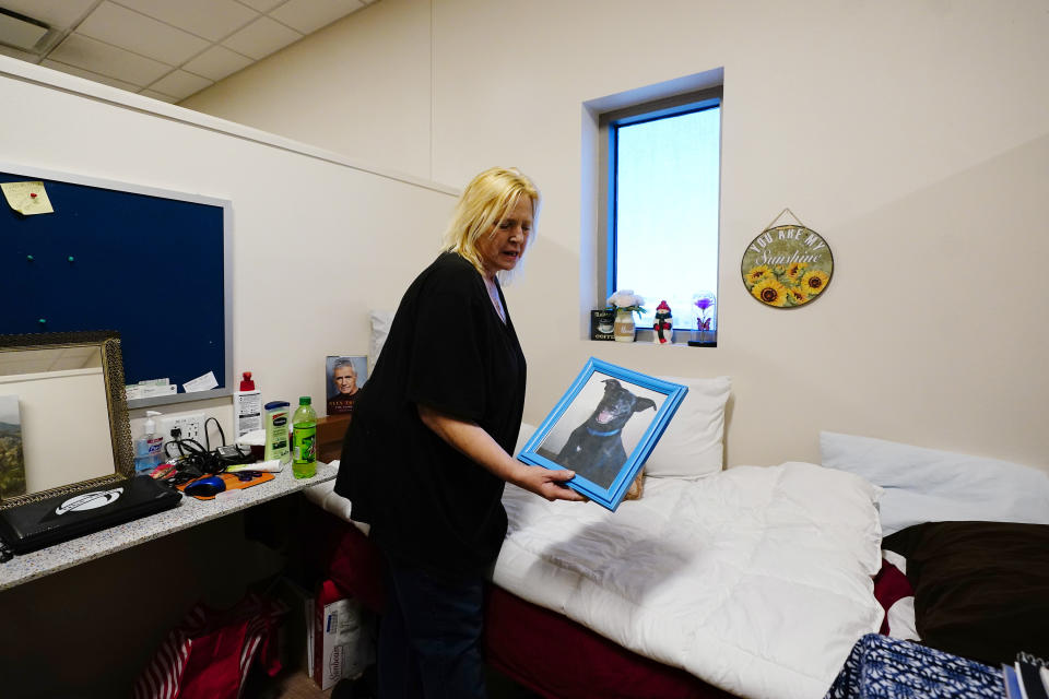 Karla Finocchio, 55, holds up a picture of her dog in her modest housing at Ozanam Manor temporary housing for people 50 and up, Friday, Feb. 4, 2022, in Phoenix. Finocchio is one face of America's graying homeless population, a rapidly expanding group of destitute and desperate people 50 and older suddenly without a permanent home after a job loss, divorce, family death or health crisis during a pandemic. (AP Photo/Ross D. Franklin)