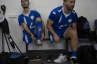 Israel Amputee Football Team players Shaked Bitton left, and Ben Binyamin wear their soccer cleats before a practice session in Ramat Gan, Thursday, April 11, 2024. The team practices two evenings a week at the stadium in the Tel Aviv suburb of Ramat Gan, first with warm-ups and drills, then practice games - each man undeterred by the absence of an arm or a leg from an accident, a war injury or a birth defect. (AP Photo/Leo Correa)