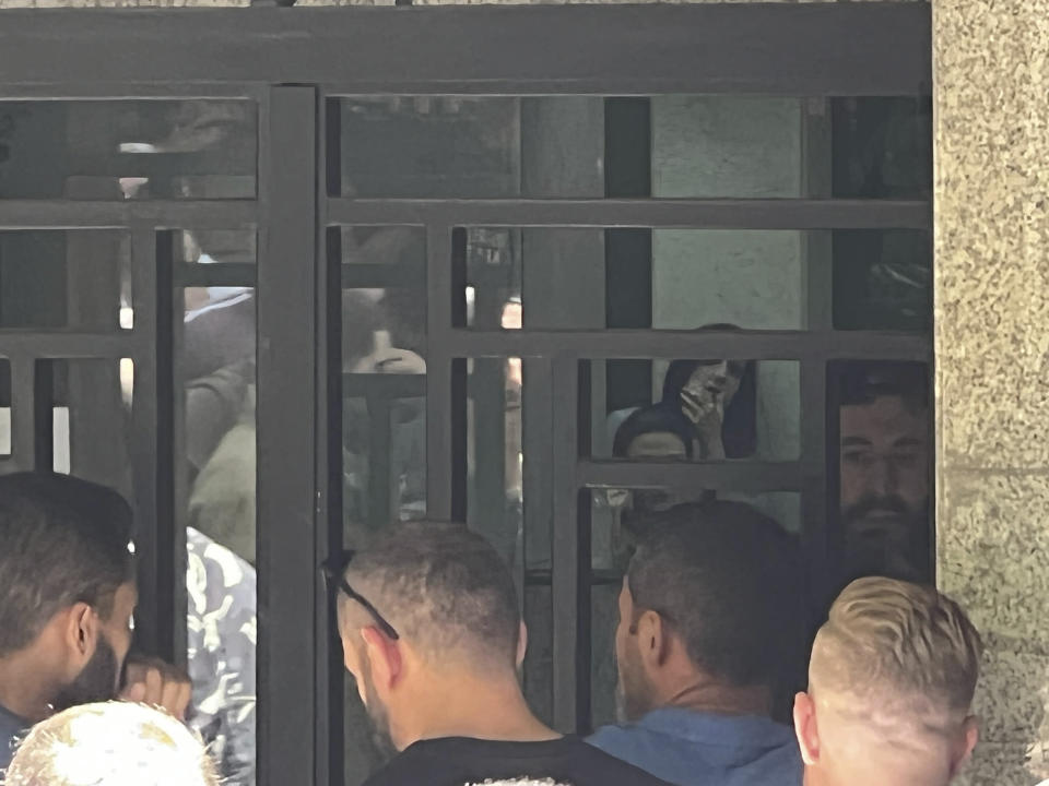 A man, with a beard, talks to police as he holds hostages at gunpoint in Beirut,, Lebanon, Thursday, Aug. 11, 2022. A Lebanese security official says a man armed with a shotgun has broken into a Beirut bank, holding employees hostage and threatening to set himself ablaze with gasoline unless he receives his trapped saving. (AP Photo/Hussein Malla)