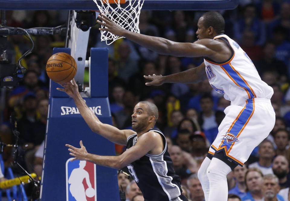 San Antonio Spurs guard Tony Parker (9) passes off from under the net in front of Oklahoma City Thunder forward Serge Ibaka (9) in the second quarter of an NBA basketball game in Oklahoma City, Thursday, April 3, 2014. (AP Photo/Sue Ogrocki)