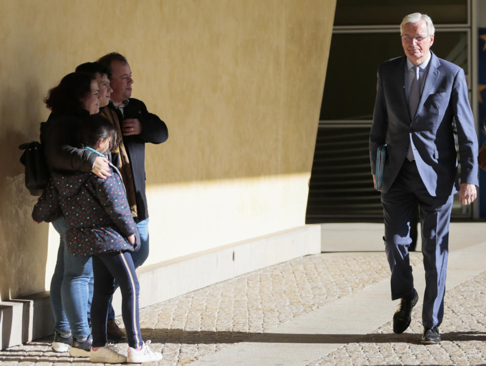 European Union chief Brexit negotiator Michel Barnier, right, walks by people posing for a photo on his way to an EU General Affairs ministers from EU headquarters in Brussels, Tuesday, Feb. 25, 2020. European Union ministers are putting the final touches on the mandate that will be the guide for EU negotiator Michel Barnier as he sits own with UK officials to thrash out a free trade deal over the next ten months. (AP Photo/Virginia Mayo)