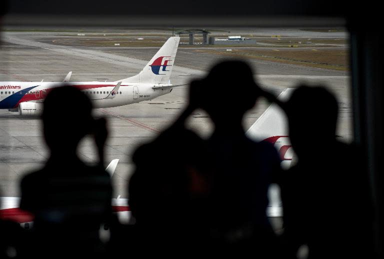 Malaysian children are silhouetted as they watch a Malaysia Airlines (MAS) plane taxi on the runway at Kuala Lumpur International Airport in Sepang on March 17, 2014