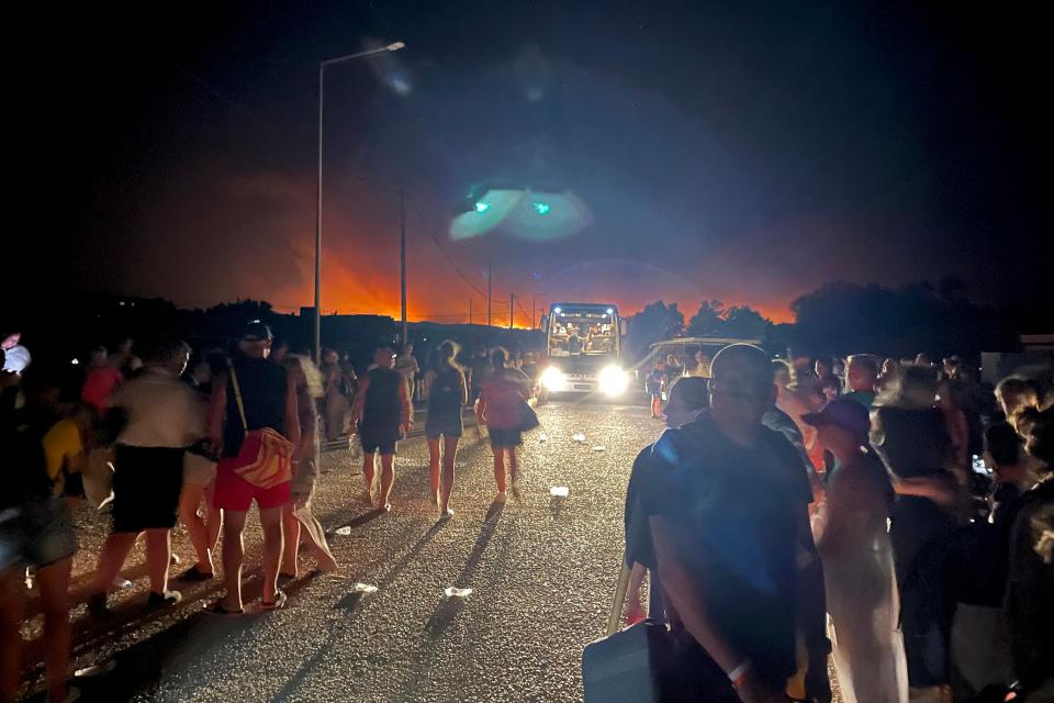 Tourists queue to get on coaches at the Gennadi Beach on the Aegean Sea Island of Rhodes, Greece (AP)