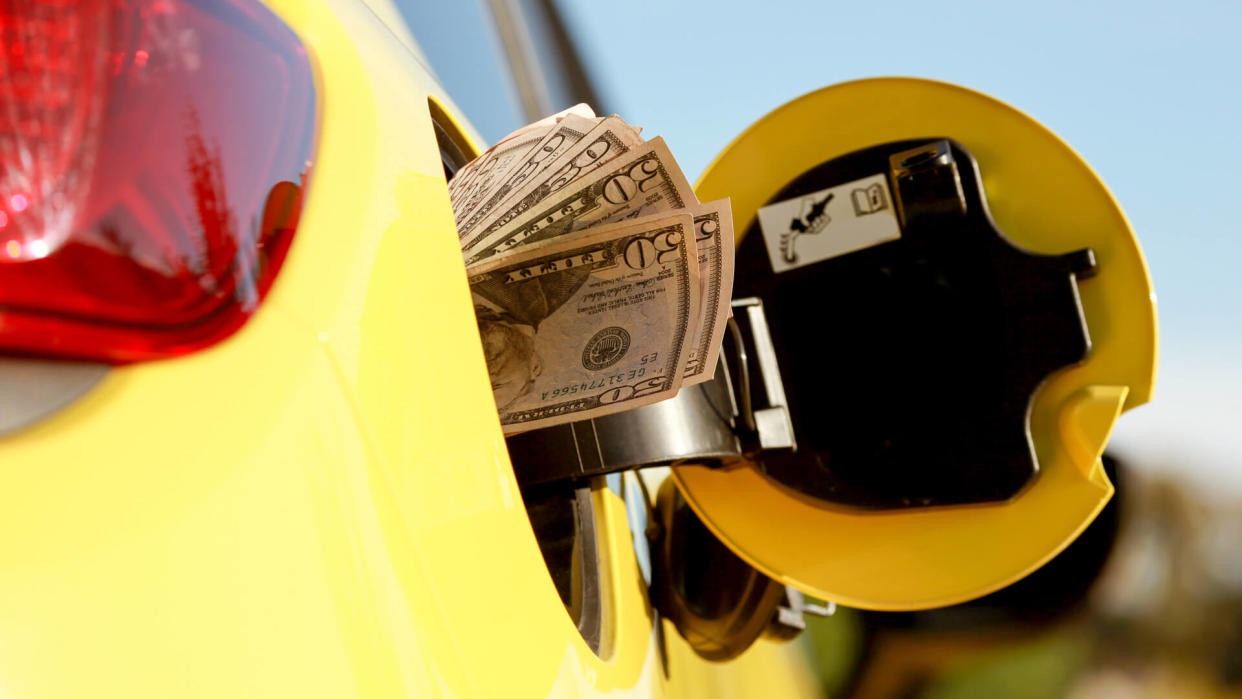 Mans Hand holding Cash while Refueling Vehicle.