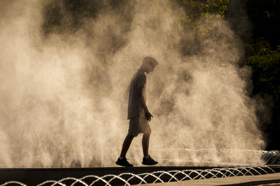A young man cools off in the drizzle from a public fountain before sunset in Bucharest, Romania, Thursday, June 20, 2024 as temperatures exceeded 38 degrees Celsius (100.4 Fahrenheit). The national weather forecaster issued a orange warning for western and southern Romania where temperatures are expected to reach 38 degrees Celsius (100.4 Fahrenheit) in the coming days. (AP Photo/Vadim Ghirda)