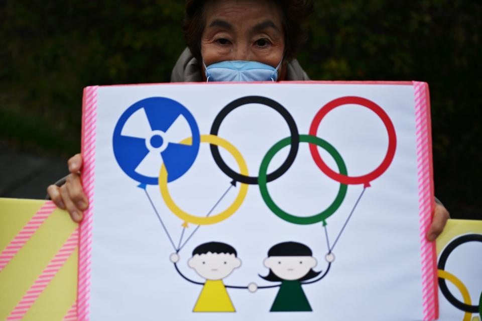 This photo taken on February 29, 2020 shows a woman holding a placard during a demonstration against the Olympics, Prime Minister Shinzo Abe and nuclear energy, near the "J-Village" which will host the start of the Olympic torch relay in Naraha, Fukushima prefecture. - Tokyo 2020 CEO Toshiro Muto said on February 26 the torch relay scheduled to begin March 26 in Fukushima and travel across the country would not be cancelled, though he acknowledged adjustments might be necessary, due to the COVID-19 outbreak. (Photo by CHARLY TRIBALLEAU / AFP) (Photo by CHARLY TRIBALLEAU/AFP via Getty Images)