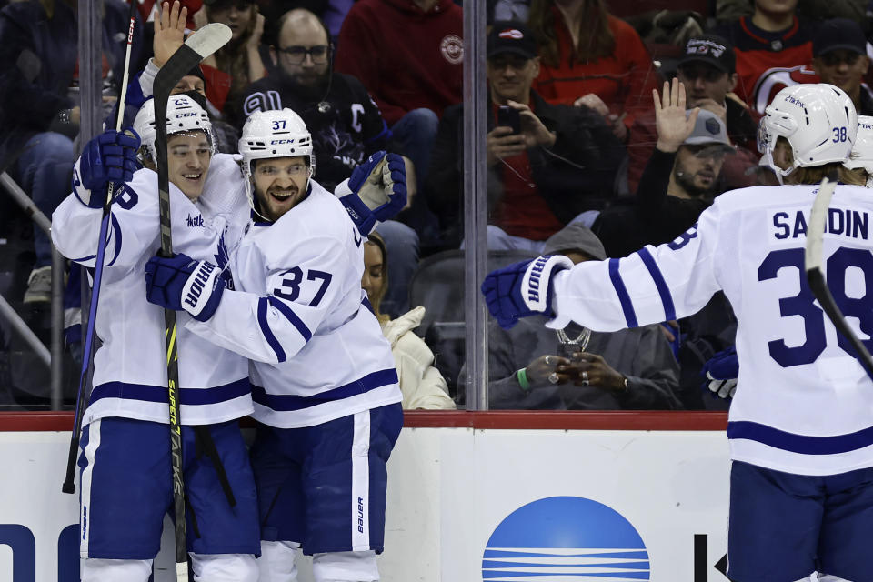 Toronto Maple Leafs right wing Pontus Holmberg, left, is congratulated by Timothy Liljegren (37) and Rasmus Sandin (38) after scoring a goal against the New Jersey Devils during the first period of an NHL hockey game Wednesday, Nov. 23, 2022, in Newark, N.J. (AP Photo/Adam Hunger)
