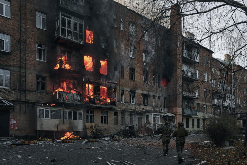 Ukrainian soldiers run to help people in an apartment building on fire after Russian shelling in Bakhmut, Donetsk region, Ukraine, Wednesday, Dec. 7, 2022. (AP Photo/LIBKOS)